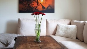 A living room with a beige sofa, a wooden coffee table, and a painting of a sunset with giraffes on the wall.