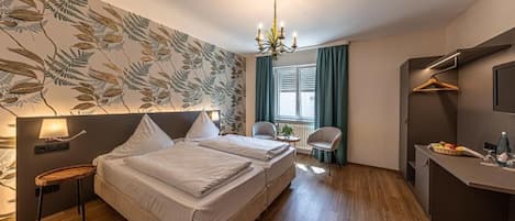 A hotel room with a bed, bedside table, lamp, and a wall with a leaf pattern.