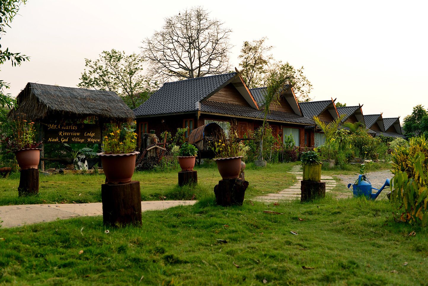 A row of traditional-style cottages with thatched roofs and potted plants in the foreground.