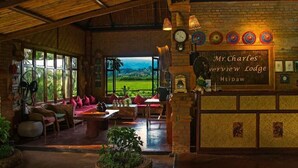 Eine gemütliche Lounge mit Korbmöbeln, eine Bar mit der Aufschrift "Mr. Charles Hsipaw Lodge" und Blick ins Freie.