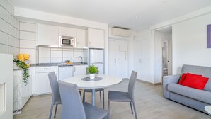 Una cocina moderna con armarios blancos, microondas y un comedor con una mesa redonda y cuatro sillas.