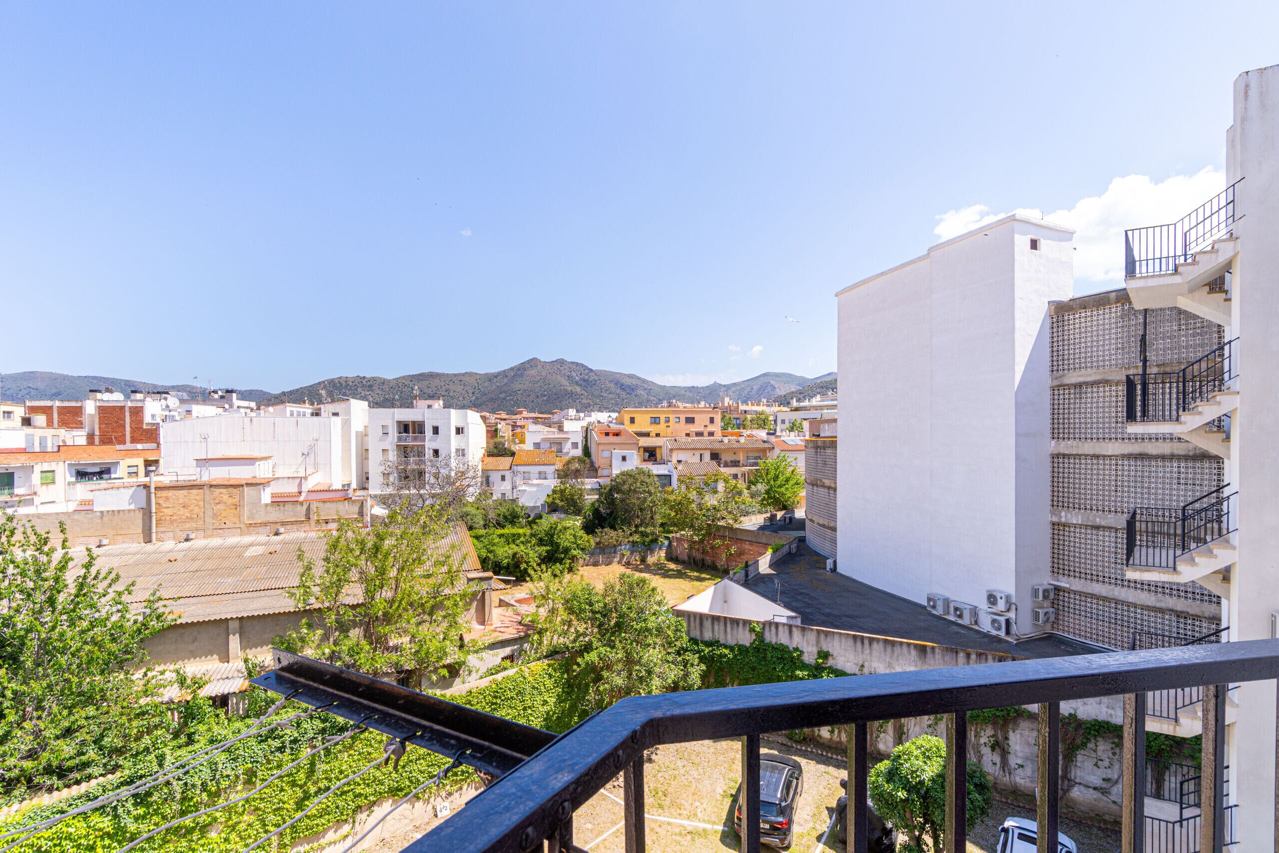 A residential area with a white building featuring multiple balconies and a staircase.