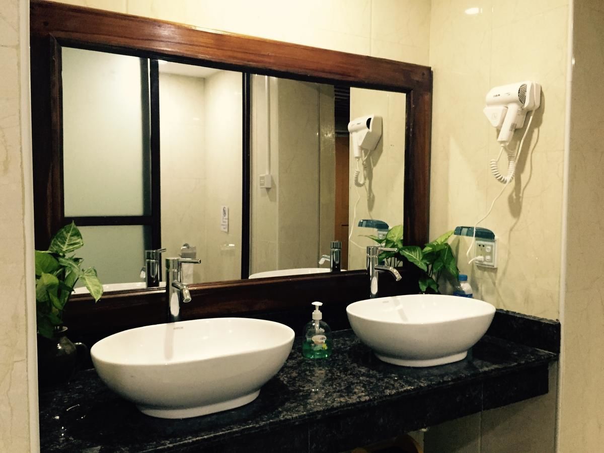 Un baño con dos lavamanos, un espejo grande y un secador de pelo montado en la pared.