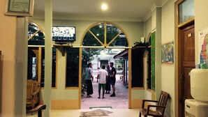 Un vestíbulo con un amplio arco, un televisor montado en la pared y un refrigerador.