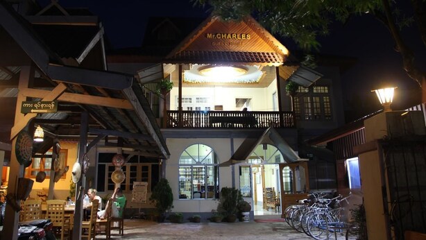 Un edificio de dos pisos con un letrero que dice 'Mr. Charles Guest House'.