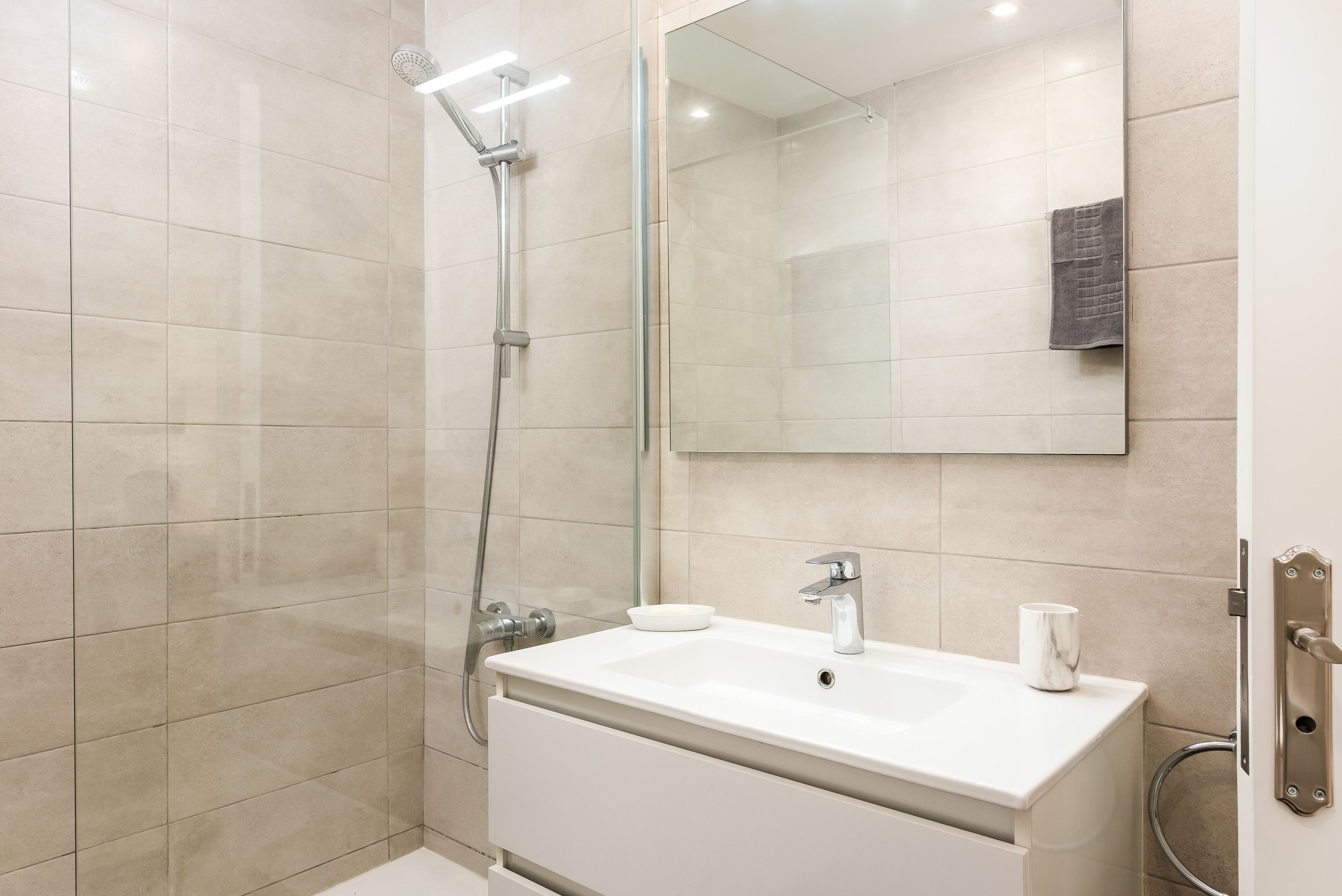 Ein modernes Badezimmer mit Dusche, Waschbecken und Spiegel.