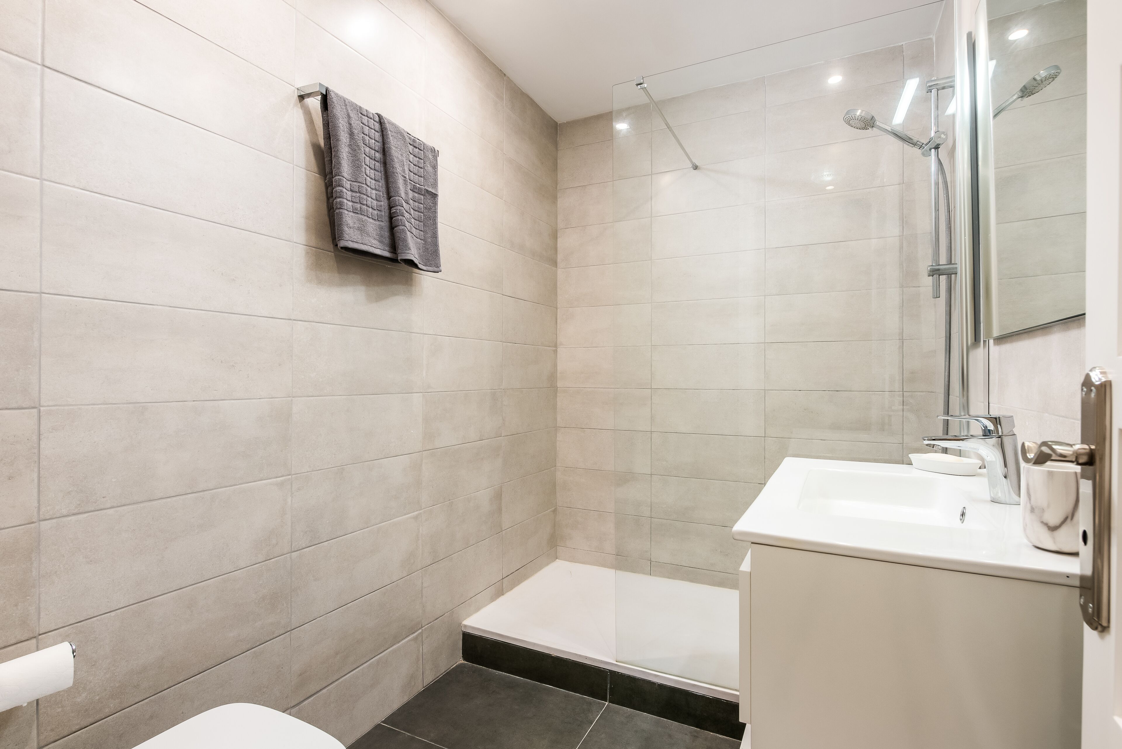 Un bagno moderno con doccia, lavandino e WC.