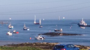 A coastal scene with various boats and a lighthouse in the background. - Greencastle B&B (Newry)
