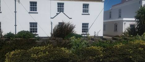 A white building with multiple windows and a stone wall in front.