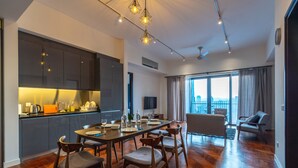 A modern kitchen with dark cabinets, a dining table set for six, and a city view through large windows. - The Mews Jalan Yap Kwan Seng by Joanne (Kuala Lumpur)