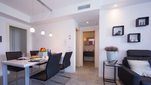 A modern dining area with a white table and black chairs, a small side table with a vase, and a black sofa with a cushion. - Casa Laura Apt. 3, Plesio, Italy (Plesio)