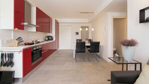 A modern kitchen with red and white cabinets, a dining area with black chairs, and a small table with a potted plant. - Casa Laura Apt. 3, Plesio, Italy (Plesio)