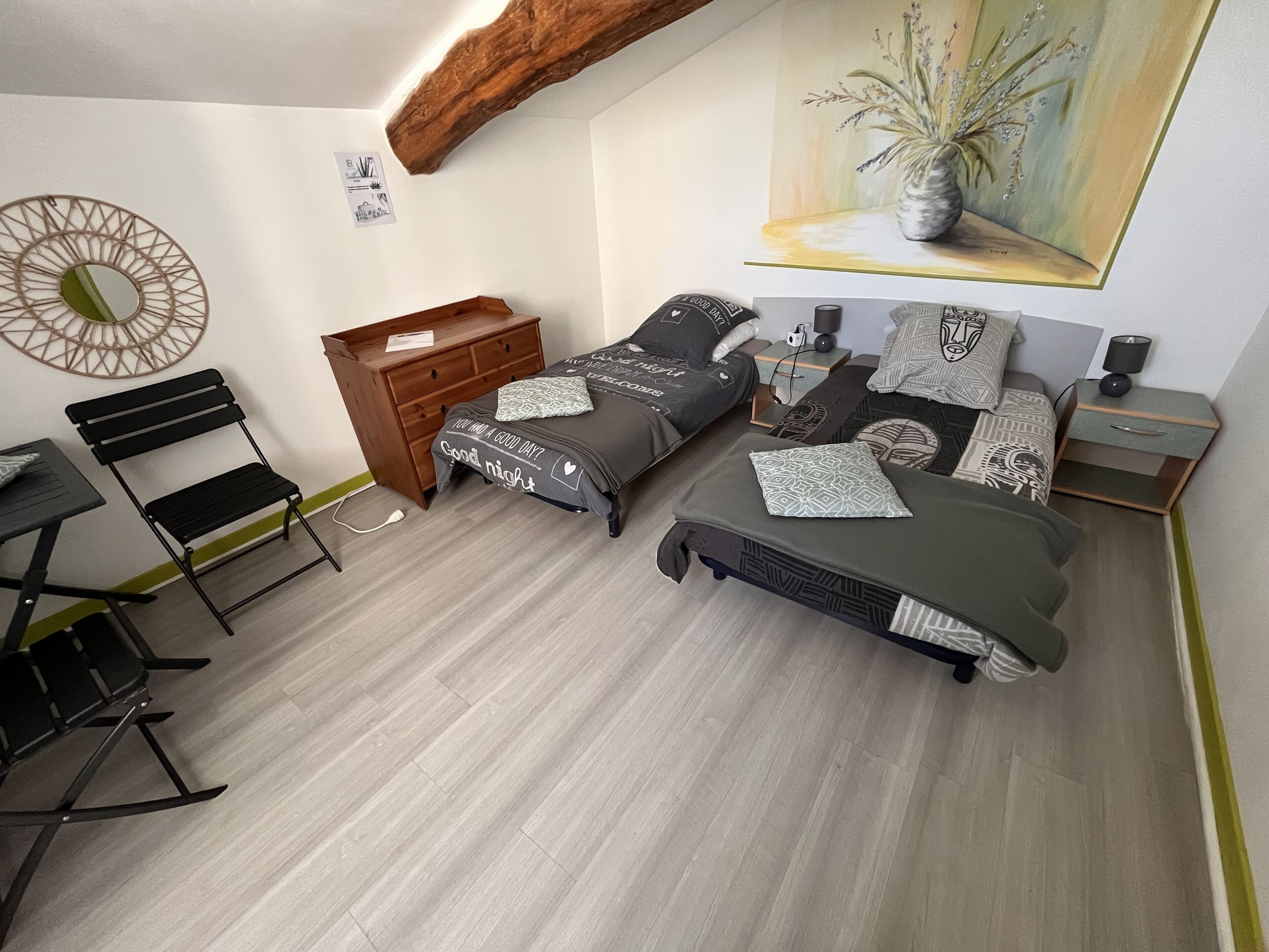 Un dormitorio con dos camas, un aparador de madera, un escritorio con una silla y un cuadro en la pared.