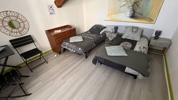 Un dormitorio con dos camas, un aparador de madera, un escritorio con una silla y un cuadro en la pared.