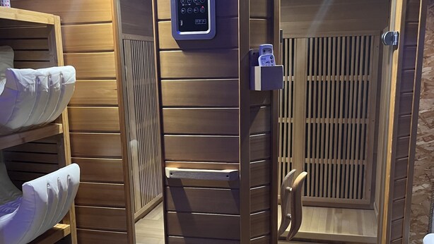 Una sauna con panel de control, listones de madera y un banco.
