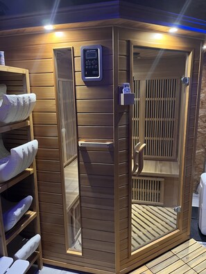 Una sauna con panel de control, listones de madera y un banco.