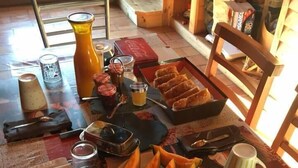 Una mesa de comedor con diferentes alimentos, como pasteles, pan y un bol de fruta.
