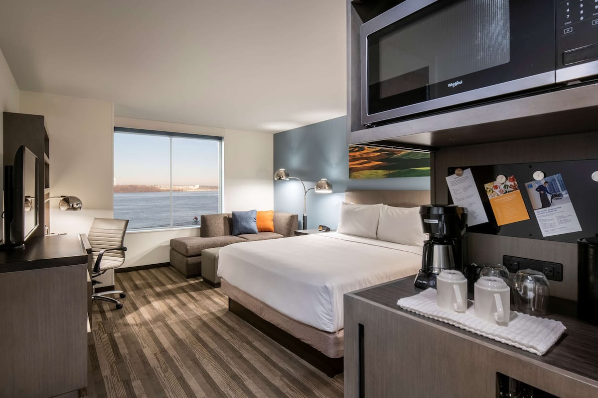 Une chambre d’hôtel équipée d’un lit, d’un bureau, d’une chaise, d’un four à micro-ondes, d’une machine à café et offrant une vue sur l’eau.