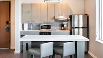 Una cocina moderna con una isla central, electrodomésticos de acero inoxidable y armarios de tonos claros.