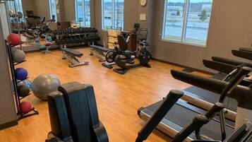 Un gimnasio con máquinas de cardio, pesas libres y pelotas de ejercicio.