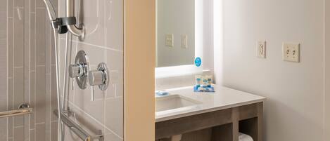 A modern bathroom with a glass-enclosed shower, a vanity with a mirror, and a towel rack.