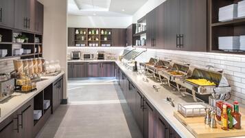 Una cocina moderna con armarios de madera oscura, una isla central con pileta y diferentes estaciones de comida.