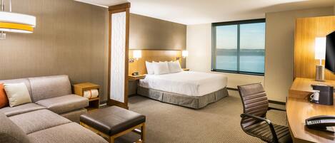 A hotel room with a bed, a sofa, a desk, and a chair.