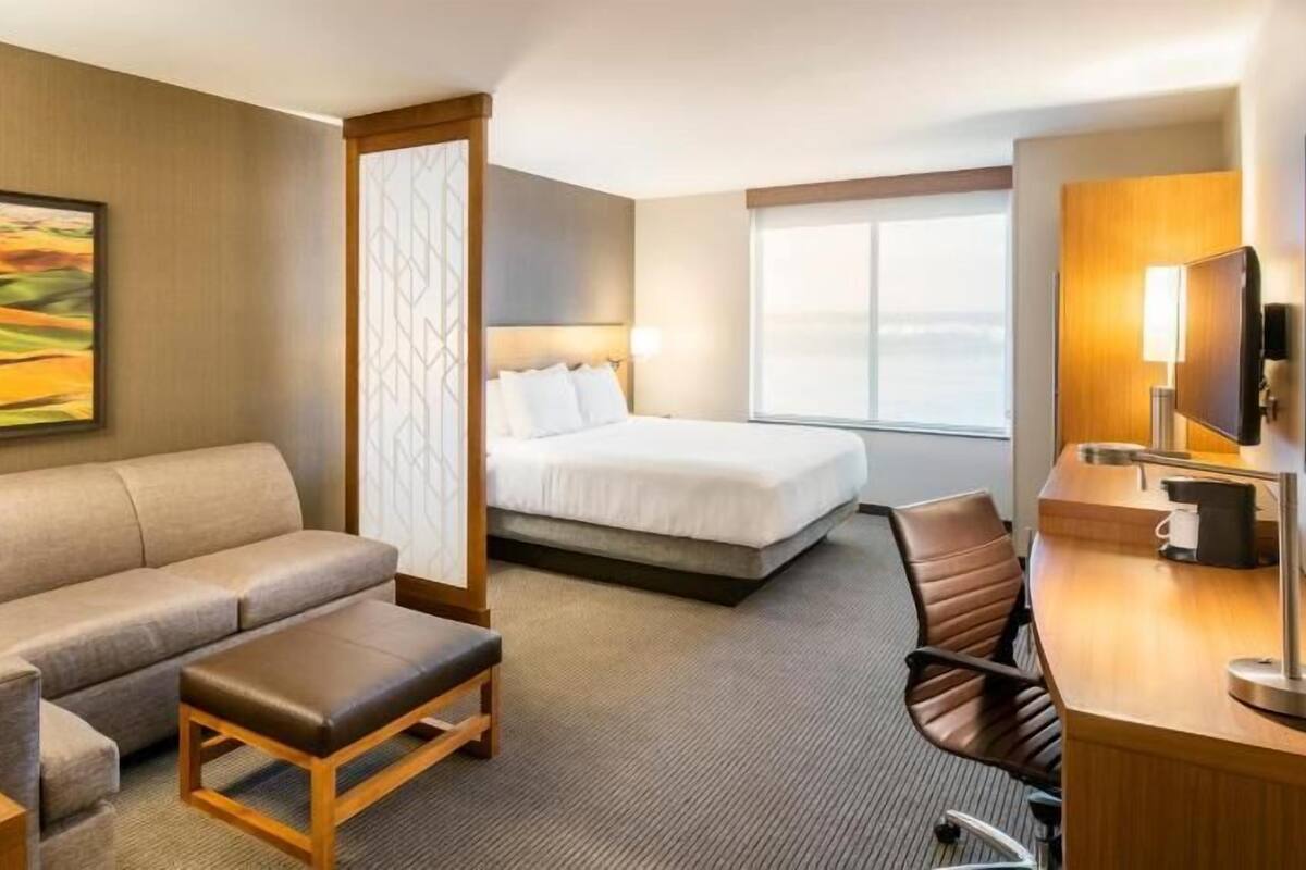 Ein Hotelzimmer mit einer Couch, einem Bett, einem Schreibtisch und einem Fernseher.