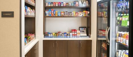 A small kitchenette area with shelves stocked with snacks and beverages, a refrigerator, and a microwave.
