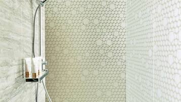 A modern bathroom with a marble wall, a shower with a glass enclosure, and a tiled floor.