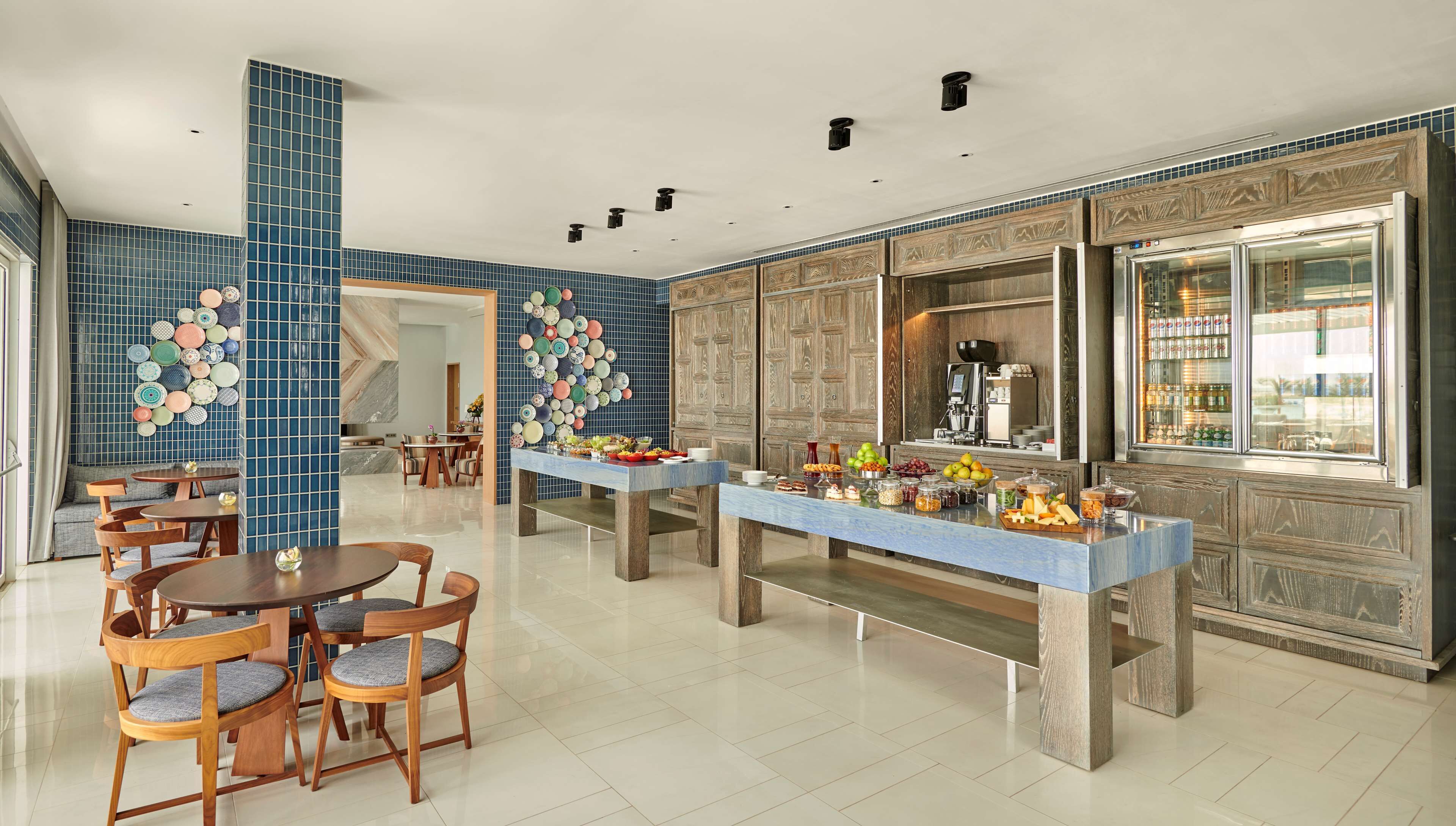 A modern dining area with a buffet setup, featuring a variety of food items and a coffee machine.