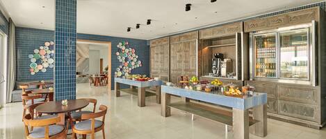 A modern dining area with a buffet setup, featuring a variety of food items and a coffee machine.