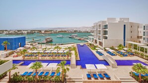 A rooftop pool area with lounge chairs and a view of a marina with boats.