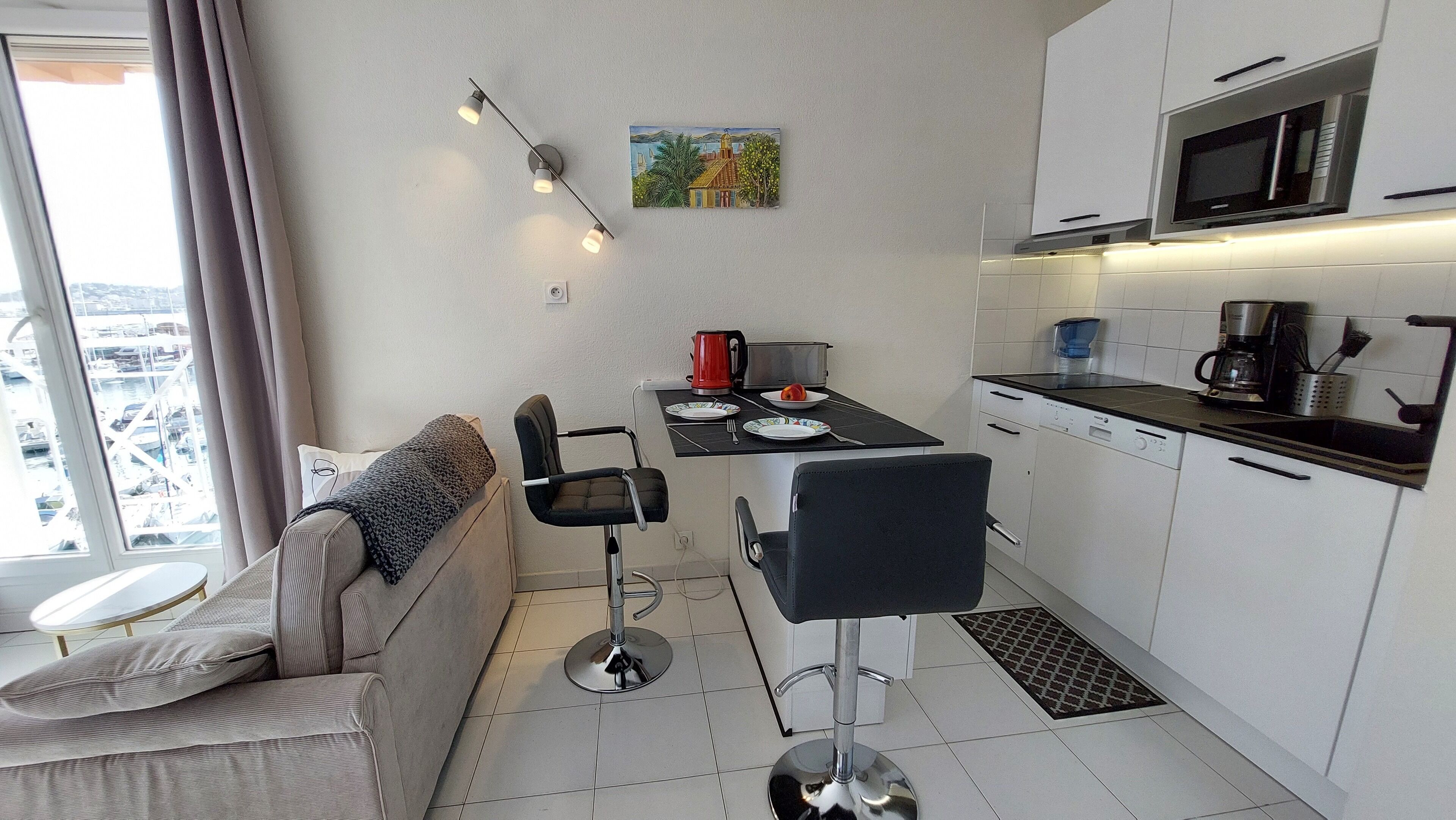 Een compacte keuken met moderne apparaten, een eettafel met stoelen en een bank met uitzicht.