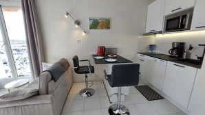 Una cocina compacta con electrodomésticos modernos, una mesa de comedor con sillas y un sofá con vistas.