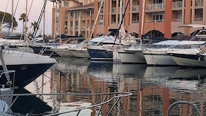 Puerto deportivo con barcos amarrados, un edificio con balcones y un flotador salvavidas.