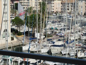 Un port de plaisance où sont amarrés de nombreux bateaux, une voiture de police et un bâtiment avec une enseigne.
