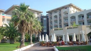 Un hotel con terraza al aire libre, palmeras y un camino central.