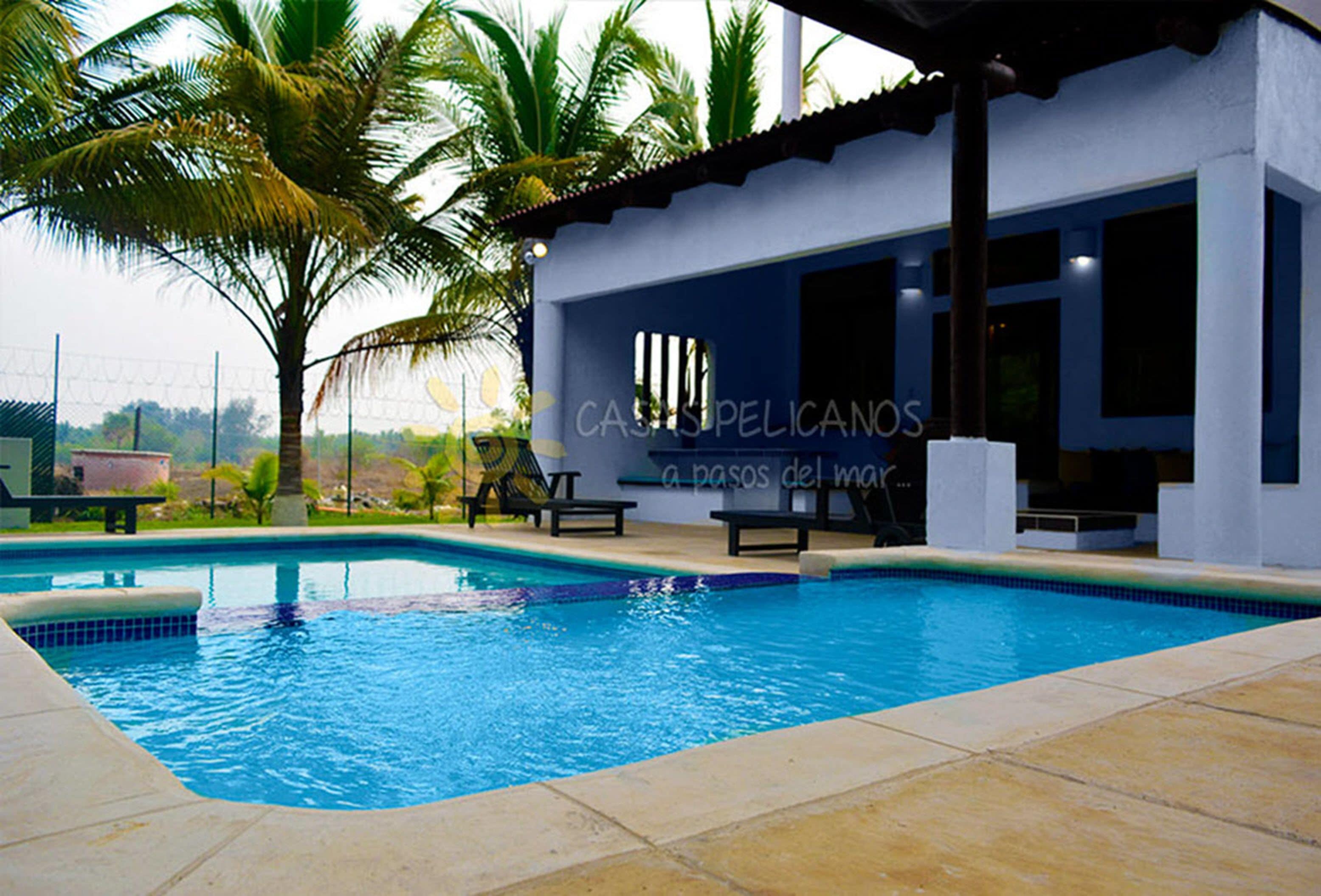 A swimming pool with lounge chairs and palm trees.