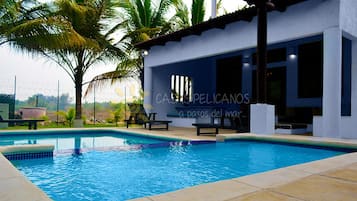A swimming pool with lounge chairs and palm trees.