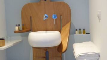 Une salle de bain avec un décor comprenant une sculpture en bois, un lavabo, un miroir et un porte-serviettes.