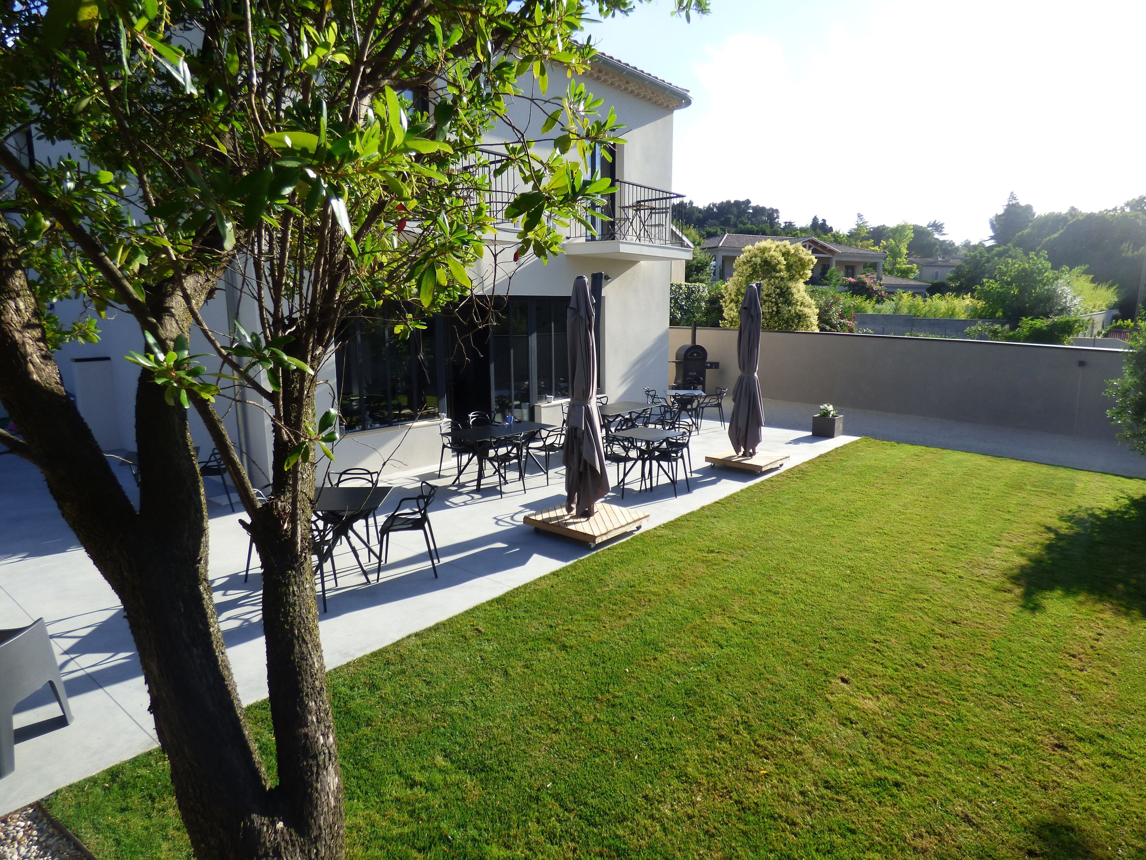 Un patio exterior moderno con mobiliario de comedor, una parrilla y una zona de estar cubierta.