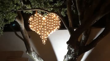 Ein Baum mit einer herzförmigen Lichtinstallation an einer Wand.