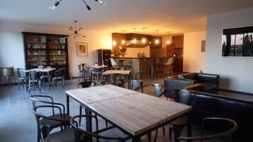 Amplia sala de estar con una mesa de comedor, varias sillas, un sofá y una cocina al fondo.