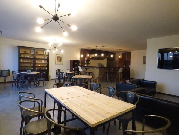 Una habitación amplia con una mesa de comedor de madera, múltiples sillas, una zona de bar y una kitchenette.