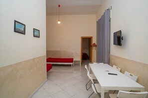 A room with a white table, chairs, a bed, and a TV mounted on the wall. - Flyresidence Garibaldi (Naples)