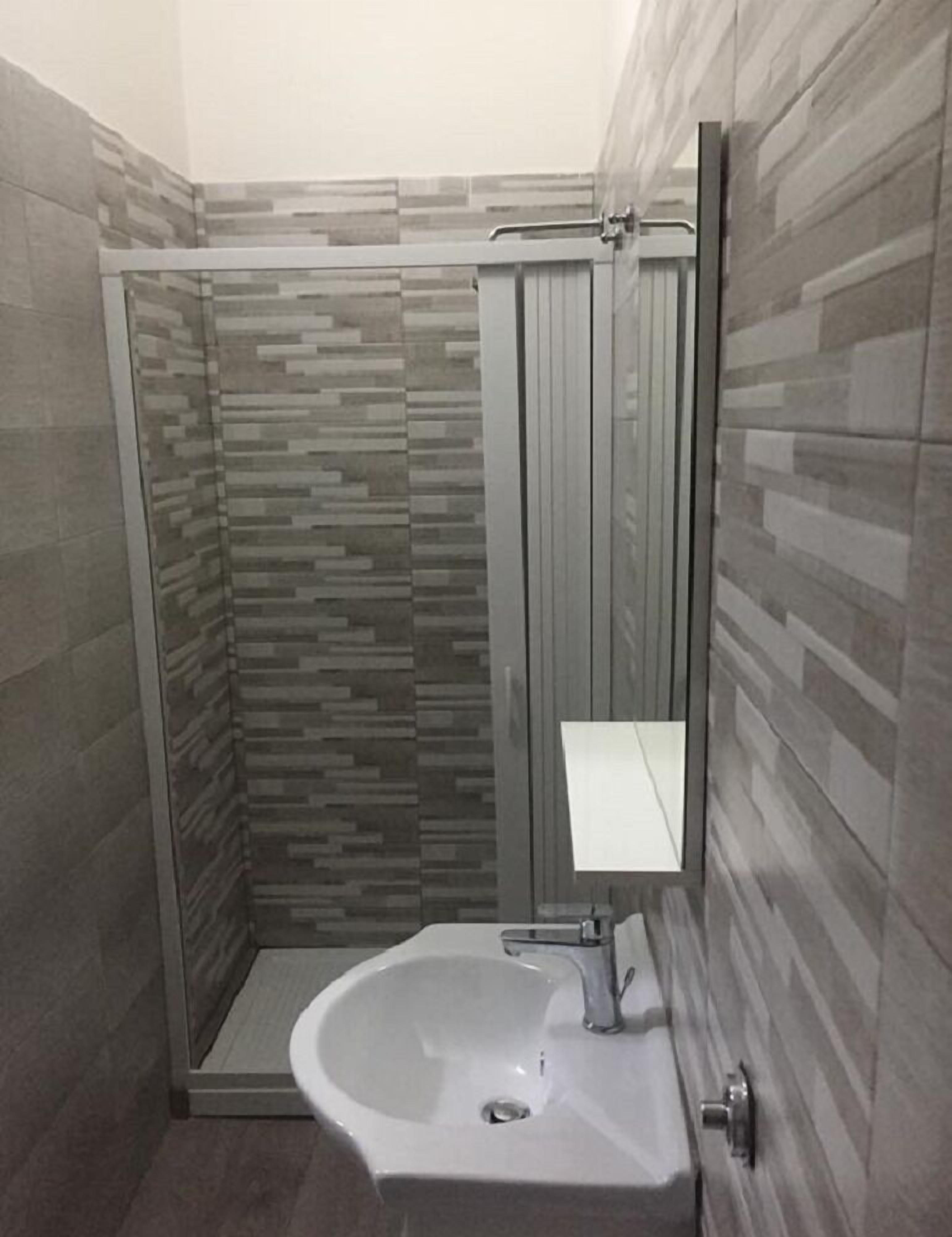 Un baño con ducha, lavamanos y espejo.