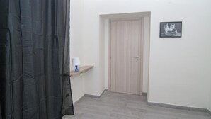 Un pasillo con una puerta de madera, un estante pequeño con una lámpara y un cuadro en la pared.