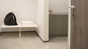 Een moderne, minimalistische badkamer met een witte wastafel, een handdoekhouder en een donkere tas op het aanrecht.