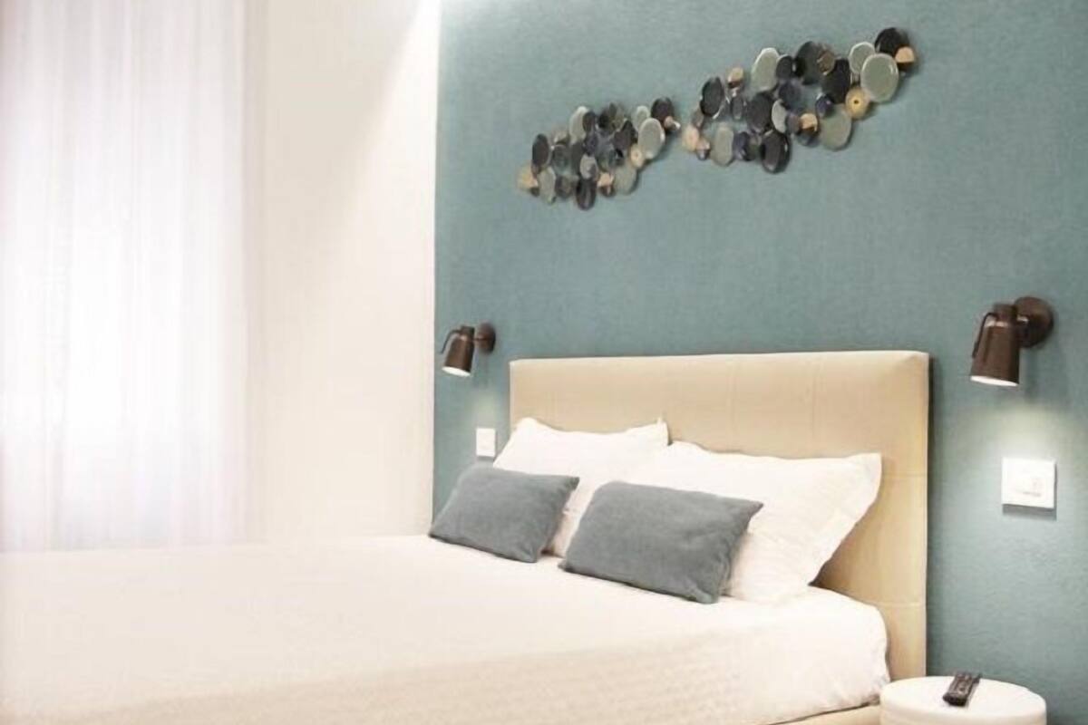 Een slaapkamer met een bed, een wandlamp en een houten plafond.